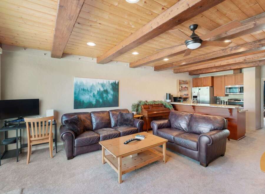 Experience rustic charm in this inviting living space featuring rich leather sofas and a warm, wood-paneled ceiling with exposed beams.