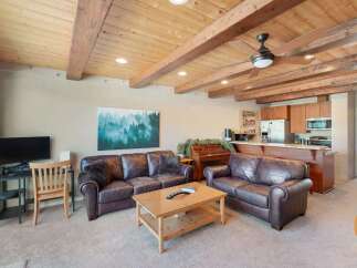 Experience rustic charm in this inviting living space featuring rich leather sofas and a warm, wood-paneled ceiling with exposed beams.