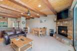 Experience cozy living in this charming room featuring a rustic stone fireplace and a warm, wood-beamed ceiling.