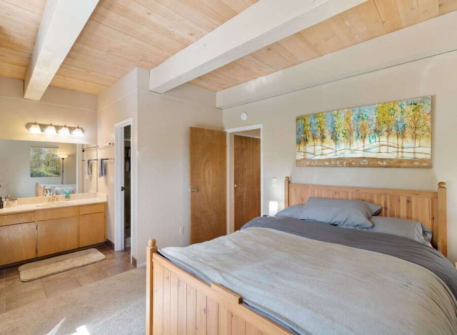 This inviting bedroom features a cozy wooden bed with soft grey linens, perfect for a restful night's sleep.