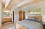 This inviting bedroom features a cozy wooden bed with soft grey linens, perfect for a restful night's sleep.