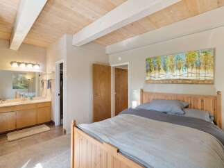 This inviting bedroom features a cozy wooden bed with soft grey linens, perfect for a restful night's sleep.