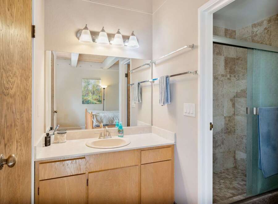 This bathroom features a spacious vanity with ample counter space and storage, complemented by a large mirror and modern light fixtures.
