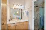 This bathroom features a spacious vanity with ample counter space and storage, complemented by a large mirror and modern light fixtures.