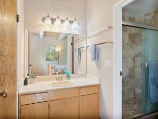 This bathroom features a spacious vanity with ample counter space and storage, complemented by a large mirror and modern light fixtures.