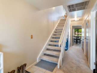 Discover comfortable living in this charming home featuring a carpeted staircase leading to the upper level.