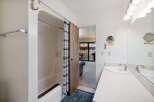 This bathroom features a bathtub with a blue and white striped shower curtain and an anchor-shaped hook.