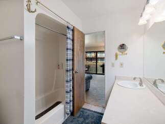 This bathroom features a bathtub with a blue and white striped shower curtain and an anchor-shaped hook.