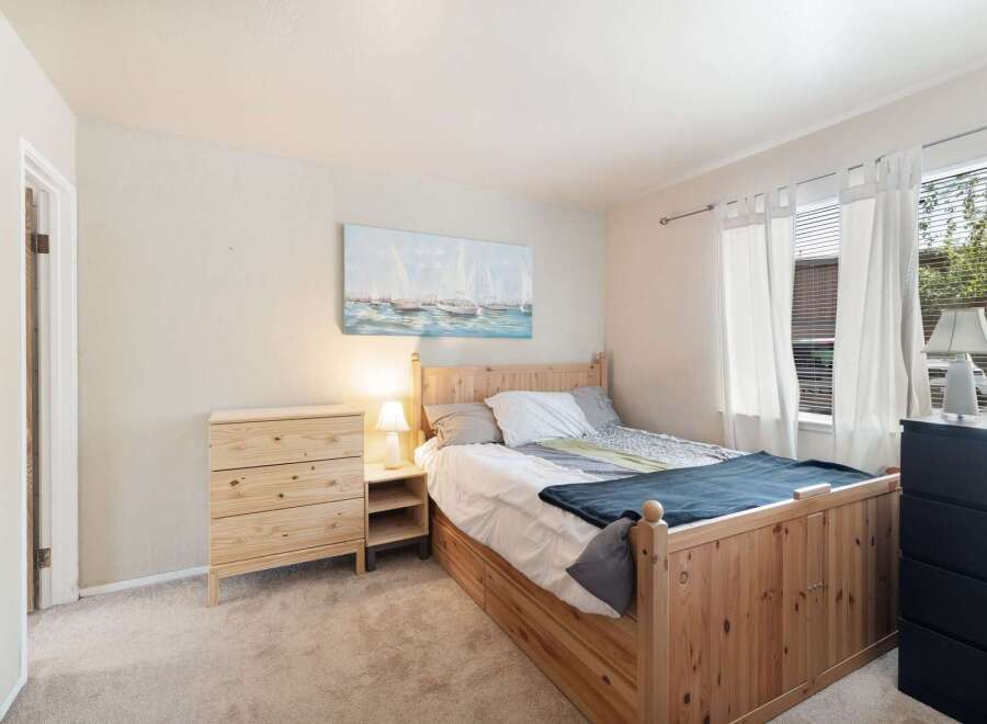 This cozy bedroom features a charming wooden bed frame with built-in storage, complemented by a matching pine dresser.