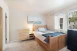 This cozy bedroom features a charming wooden bed frame with built-in storage, complemented by a matching pine dresser.