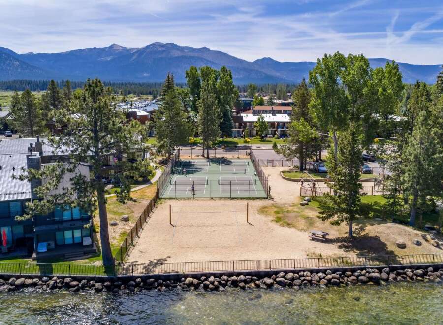 Enjoy lakeside living with this stunning property featuring a private beach volleyball court and multiple tennis courts for recreation.