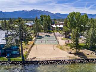 Enjoy lakeside living with this stunning property featuring a private beach volleyball court and multiple tennis courts for recreation.