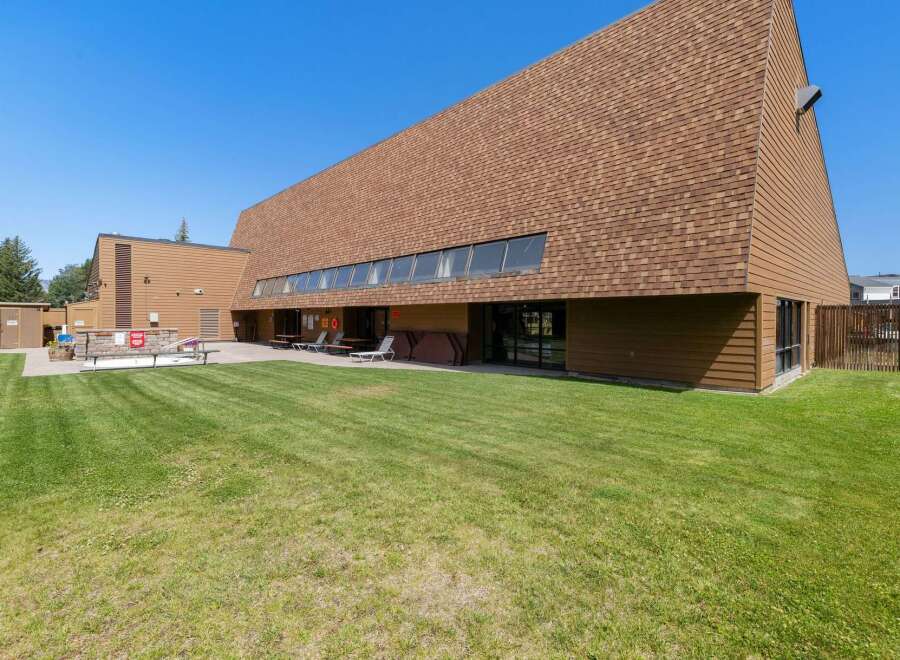 Enjoy outdoor living with a spacious green lawn and a paved patio area perfect for entertaining.