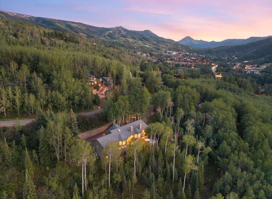 Nestled amidst a lush aspen and pine forest, this stunning mountain home offers breathtaking panoramic views of the surrounding peaks and a charming ski village below.
