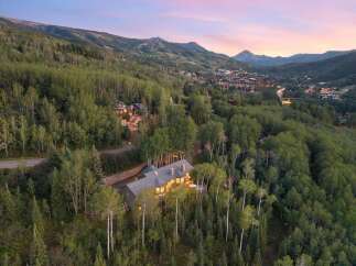 Nestled amidst a lush aspen and pine forest, this stunning mountain home offers breathtaking panoramic views of the surrounding peaks and a charming ski village below.