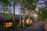 Nestled amongst tall aspen trees, this charming home offers a warm and inviting ambiance, especially as dusk settles.