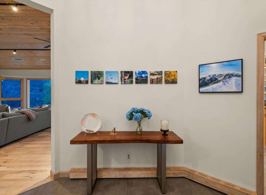 This entryway features a live-edge wood console table adorned with decorative items and a vase of blue hydrangeas.