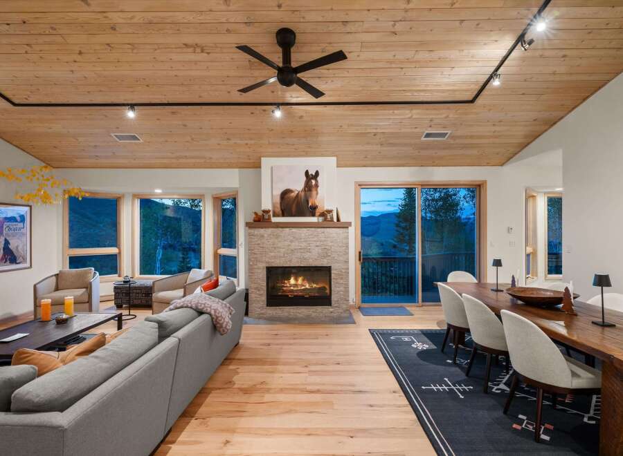 Experience luxurious mountain living in this stunning open-concept great room, featuring a cozy stone fireplace and a beautiful wooden ceiling.