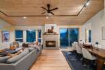 Experience luxurious mountain living in this stunning open-concept great room, featuring a cozy stone fireplace and a beautiful wooden ceiling.