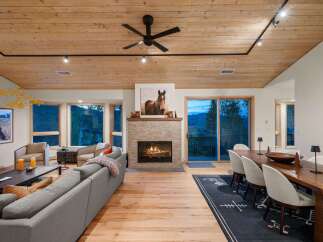Experience luxurious mountain living in this stunning open-concept great room, featuring a cozy stone fireplace and a beautiful wooden ceiling.