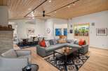 Experience modern living in this spacious open-concept living and dining area, featuring a stunning wood-paneled ceiling and a cozy sectional sofa.