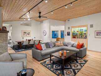 Experience modern living in this spacious open-concept living and dining area, featuring a stunning wood-paneled ceiling and a cozy sectional sofa.