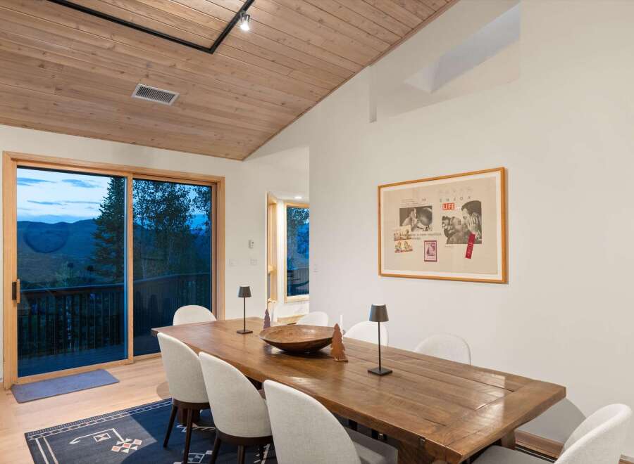 Experience breathtaking mountain views from this elegant dining room, featuring a rustic wooden table and chairs perfect for intimate gatherings.