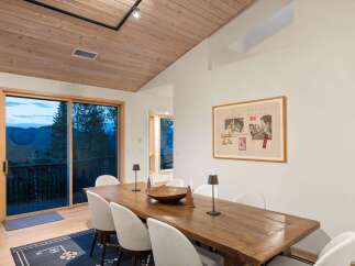 Experience breathtaking mountain views from this elegant dining room, featuring a rustic wooden table and chairs perfect for intimate gatherings.