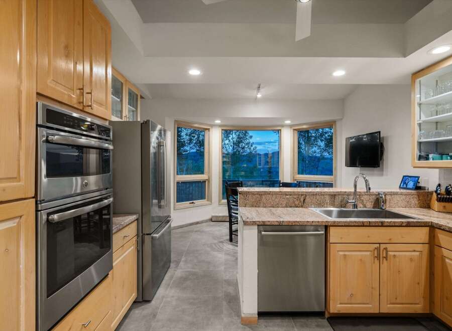 Experience breathtaking mountain views from this stunning kitchen, featuring a double oven and stainless steel refrigerator.