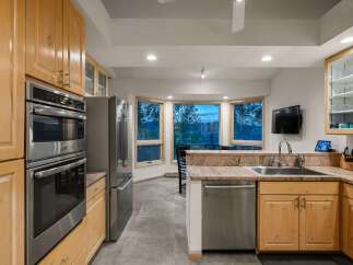 Experience breathtaking mountain views from this stunning kitchen, featuring a double oven and stainless steel refrigerator.