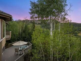 Experience ultimate relaxation on this expansive deck, complete with a luxurious hot tub and comfortable seating, perfect for enjoying the stunning mountain views.