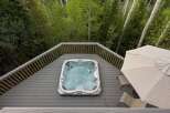 Experience ultimate relaxation in this luxurious hot tub, perfectly situated on a spacious deck surrounded by lush greenery.