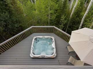 Experience ultimate relaxation in this luxurious hot tub, perfectly situated on a spacious deck surrounded by lush greenery.
