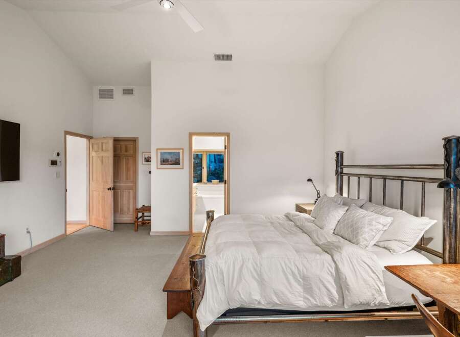 Experience ultimate comfort in this spacious bedroom, featuring a vaulted ceiling and a cozy seating area.