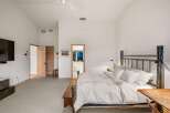 Experience ultimate comfort in this spacious bedroom, featuring a vaulted ceiling and a cozy seating area.