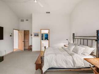 Experience ultimate comfort in this spacious bedroom, featuring a vaulted ceiling and a cozy seating area.