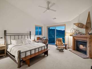 Experience ultimate comfort in this luxurious bedroom, featuring a cozy fireplace and a stunning mountain view from the sliding glass doors.