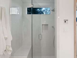 Experience luxury in this modern bathroom featuring a spacious glass-enclosed shower with a built-in bench and a sleek shower system.