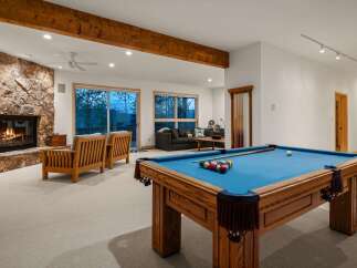 Experience ultimate relaxation and entertainment in this stunning basement living area, featuring a cozy stone fireplace and a full-size pool table for endless fun.