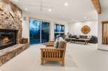 Experience breathtaking mountain views from this stunning living room, featuring a grand stone fireplace and expansive sliding glass doors that open to a scenic deck.