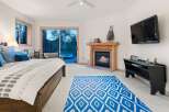 Experience ultimate relaxation in this luxurious bedroom featuring a cozy fireplace and a private balcony with a hot tub overlooking a serene forest.