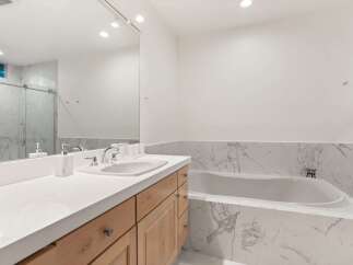 Experience modern luxury in this stunning bathroom, featuring a sleek vanity with ample counter space and a deep soaking tub perfect for relaxation.