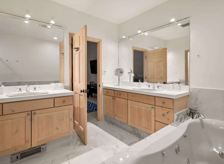This luxurious bathroom features dual vanities with ample counter space and natural wood cabinetry.