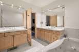 This luxurious bathroom features dual vanities with ample counter space and natural wood cabinetry.