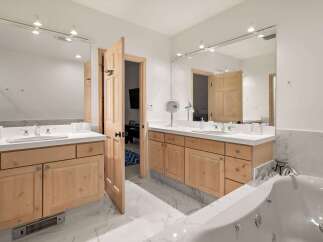 This luxurious bathroom features dual vanities with ample counter space and natural wood cabinetry.