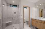 Experience modern luxury in this stunning bathroom featuring a spacious marble-tiled shower with a built-in bench and sleek glass enclosure.