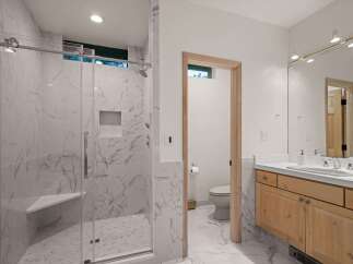 Experience modern luxury in this stunning bathroom featuring a spacious marble-tiled shower with a built-in bench and sleek glass enclosure.