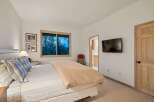 Experience serene mountain living in this charming bedroom, featuring a comfortable bed adorned with plaid pillows and a cozy duvet.