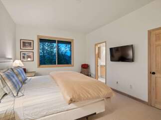 Experience serene mountain living in this charming bedroom, featuring a comfortable bed adorned with plaid pillows and a cozy duvet.