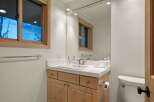 This bathroom features a clean and modern vanity with ample storage space, complemented by a large mirror reflecting the natural light from the window.